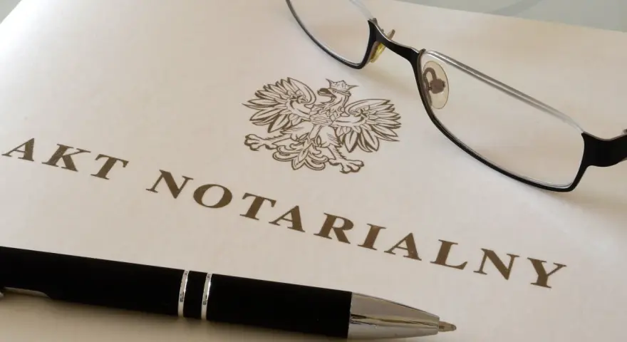 Akt notarialny z orłem, długopis i okulary.