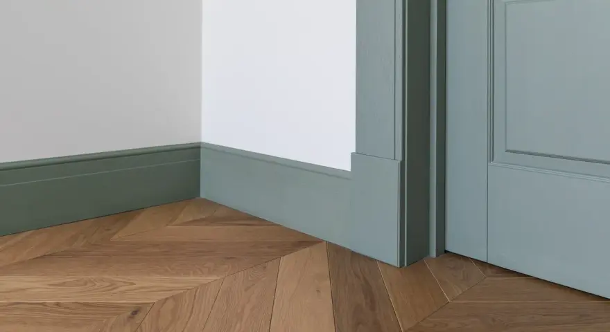 Elegancka listwa przypodłogowa w kolorze miętowym, z widocznymi wymiarami, idealnie komponuje się z drewnianą podłogą ułożoną we wzór jodełki.