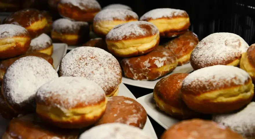 Puszyste pączki z piekarnika, niektóre oprószone cukrem pudrem, inne błyszczące od lukru. Idealne na tłusty czwartek!
