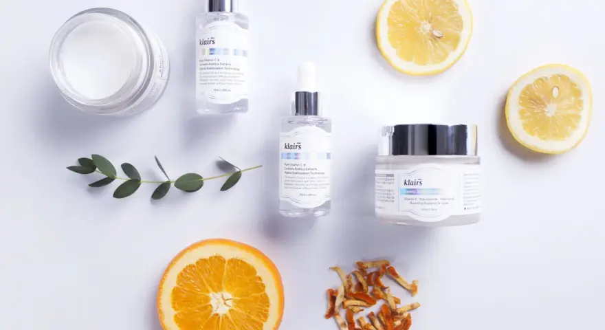 Hudvårdsprodukter från Klairs med C-vitaminserum och en kräm med e-vitamin hud för lyster. Citron- och apelsinskivor som dekoration.