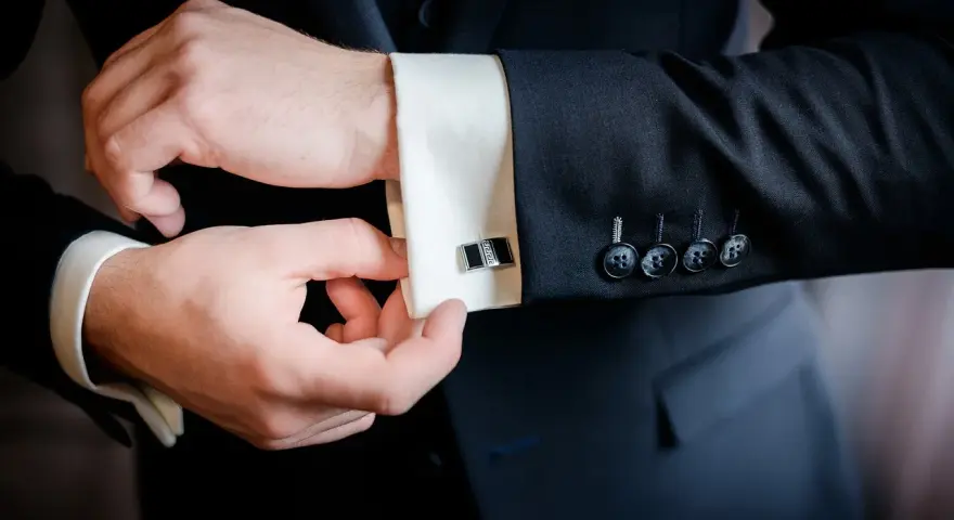 Mężczyzna zapina eleganckie spinki do mankietów koszuli. Dowiedz się, jak zapiąć spinki do koszuli, by wyglądać stylowo.