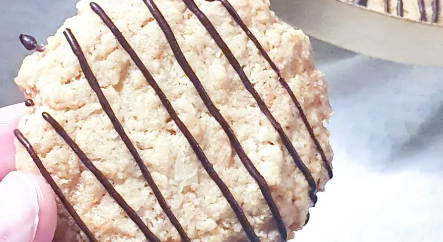 En hand håller en chokladglaserad havrekaka. Perfekt för ett enkelt havrekakor recept.
