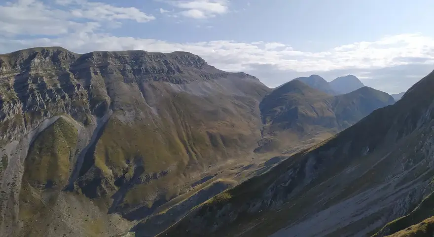 Vaste montagne del Monte Corvo sotto un cielo azzurro con nuvole bianche.