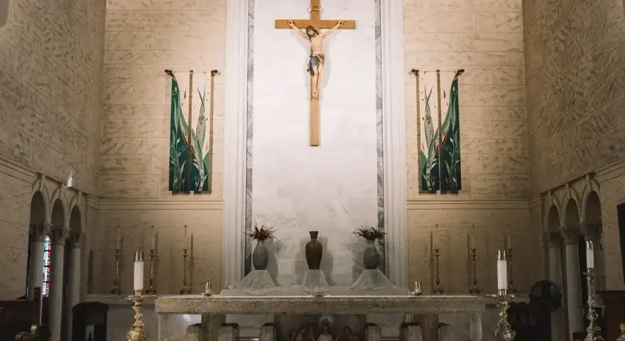 Ołtarz w kościele z krzyżem i świecami. W tle wiszą ozdobne banery. Szukasz imiona do bierzmowania męskie?