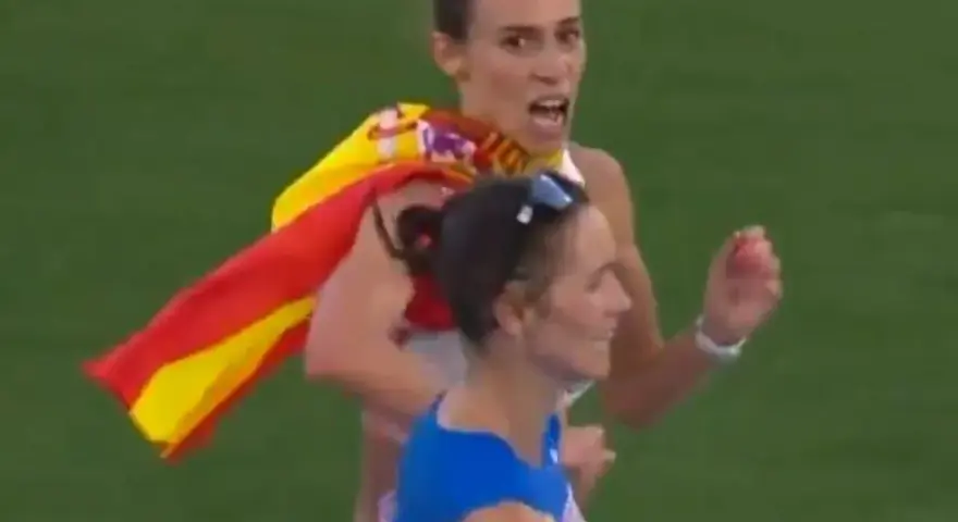 Laura García Caro celebra su victoria en atletismo, ondeando la bandera española con orgullo.