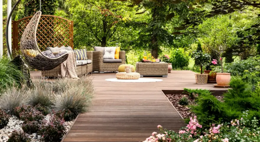 Un rincón acogedor con muebles de mimbre, una hamaca colgante y flores, ideal para disfrutar de pequeños jardines.