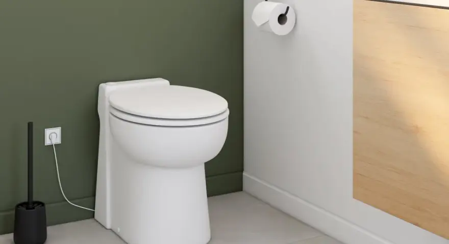 Toilettes modernes avec un sanibroyeur discret, dont le fonctionnement est assuré par une prise électrique visible.