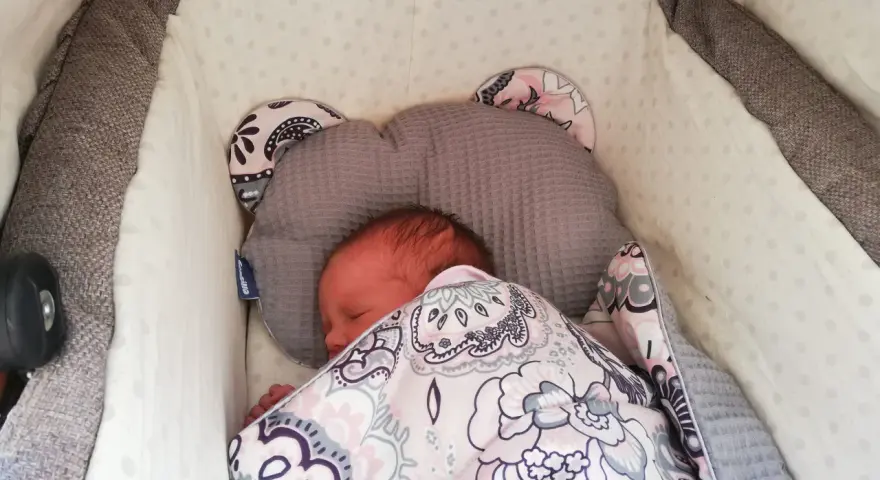 Malutkie dziecko śpi w wózku, otulone kolorowym kocykiem. To pierwszy spacer, czas na drzemkę.