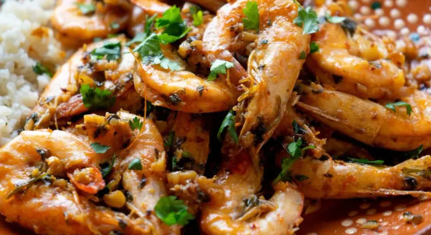 Langostinos en salsa, jugosos y llenos de sabor, servidos con arroz blanco. Un plato que invita a disfrutar.