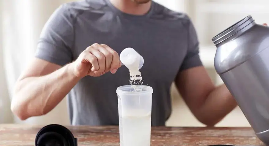 Hombre preparando un batido. Sabe cuándo tomar BCAA para optimizar su entrenamiento.
