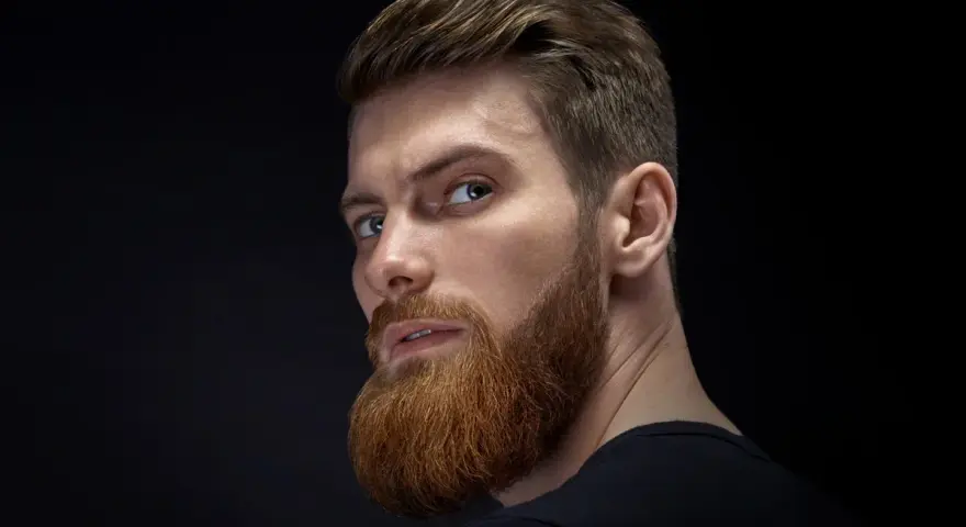 Hombre con barba rojiza y peinado actual, con el pelo peinado hacia atrás y un corte moderno.