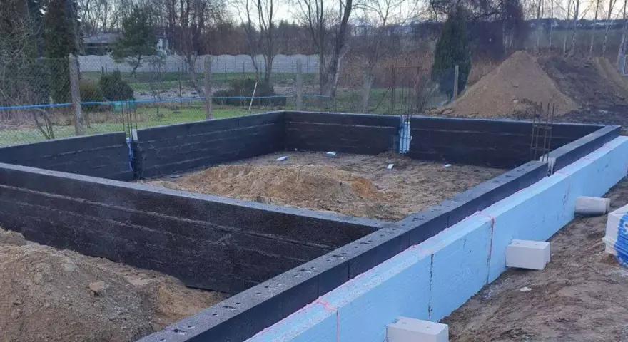 Budowa domu: fundamenty z bloczków fundamentowych i styropianu. Widać zbrojenie i przygotowanie pod wylewanie betonu.