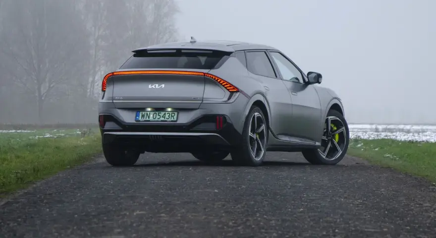 Szare Kia EV6 GT z żółtymi zaciskami hamulcowymi na tle mglistego krajobrazu.