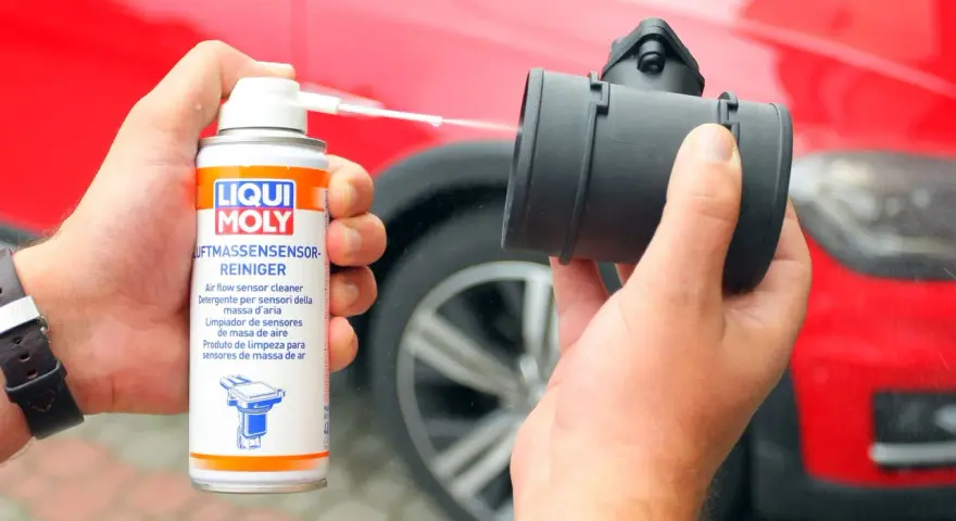 Czyszczenie przepływomierza: ręka trzyma puszkę preparatu Liqui Moly i aplikuje go na element.