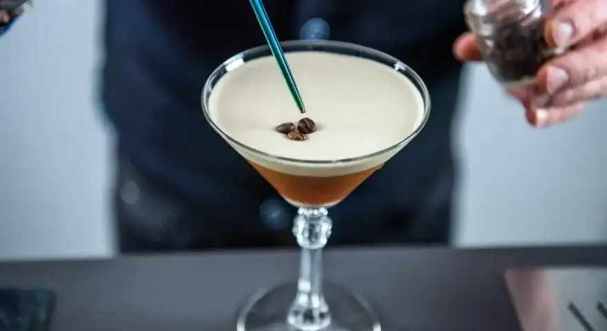 Barman dodaje ziarna kawy do drinka z pianką, idealny likier 43 zamiennik.