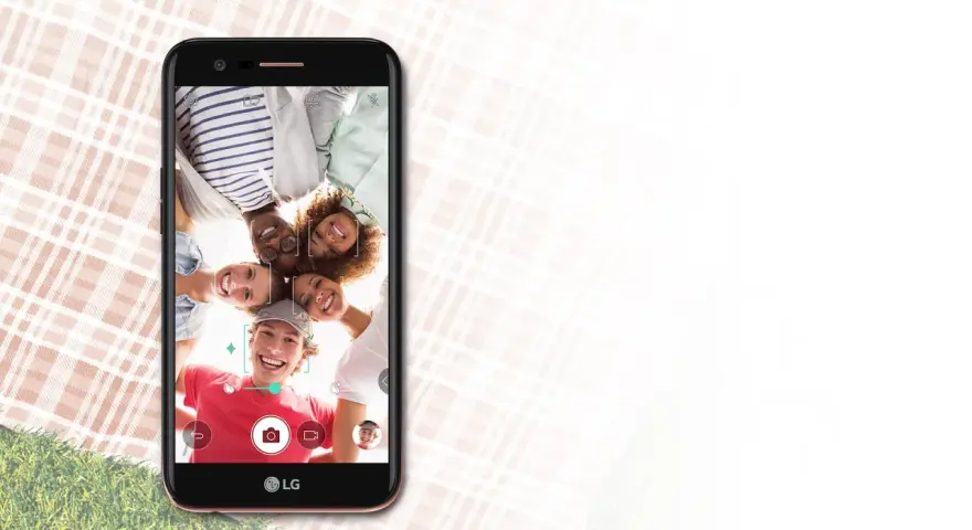 Uśmiechnięta grupa przyjaciół robi selfie telefonem LG K10 2017 Dual na pikniku.