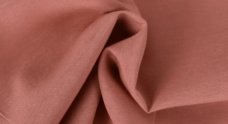 Tessuto twill color salmone, ideale per capi invernali o estivi, con pieghe morbide che ne esaltano la trama.