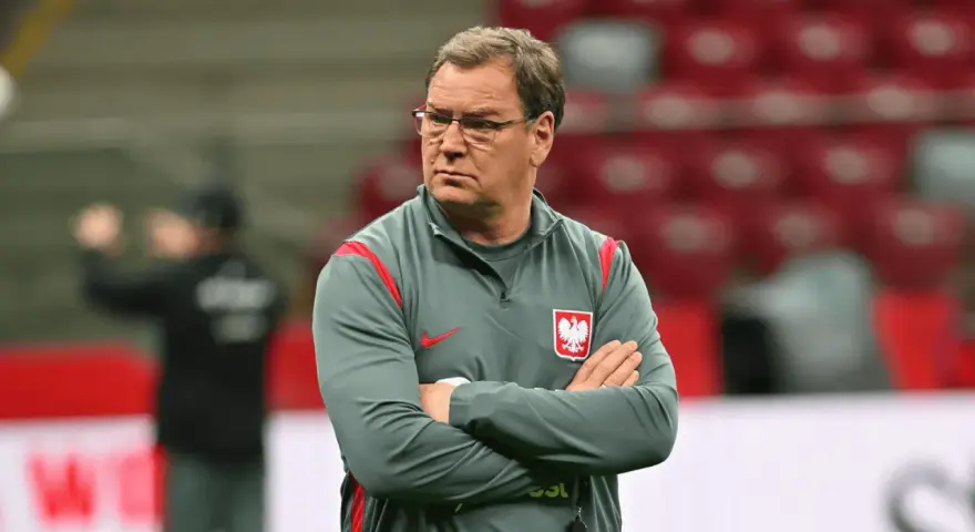 Trener reprezentacji Polski w piłce nożnej, z założonymi rękami, w okularach, zastanawia się, ile zarabia.