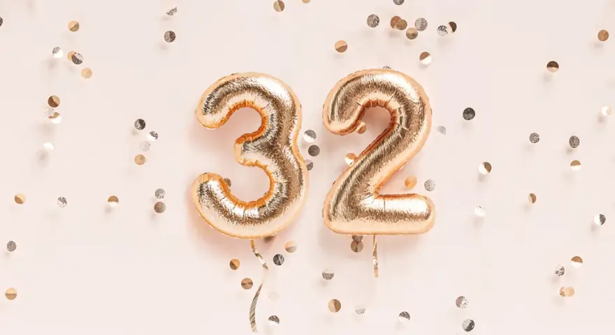 Złote balony z cyframi 3 i 2, otoczone konfetti. To już 32 tydzień ciąży, który to miesiąc?