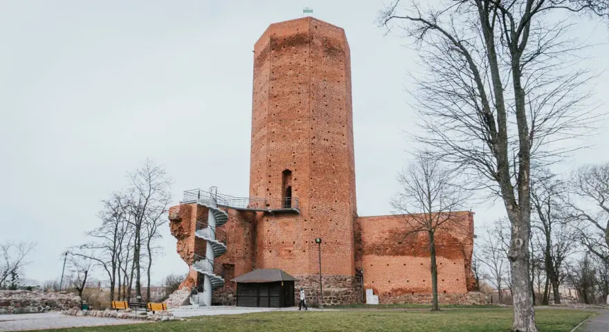 Wysoka, ceglana wieża w mieście, przypominająca mysią wieżę, z kręconymi schodami na zewnątrz.