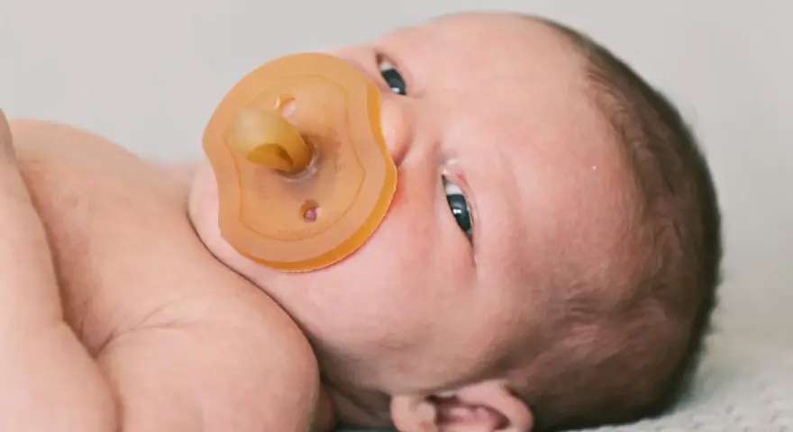 Neugeborenes Baby mit Schnuller. Die Frage "ab wann Schnuller geben" beschäftigt viele Eltern.