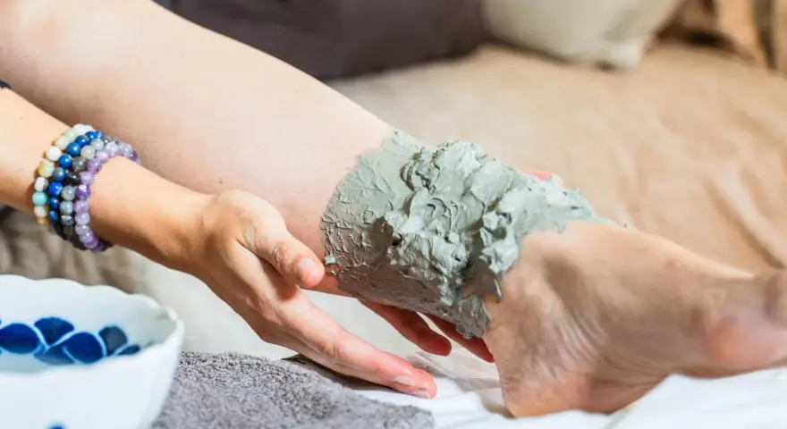 Application d'argile verte sur une jambe, profitant de ses bienfaits détoxifiants et apaisants pour la peau.