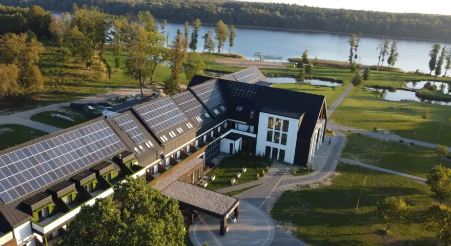 Nowoczesny hotel z panelami słonecznymi nad jeziorem, idealny na Mazury all inclusive.