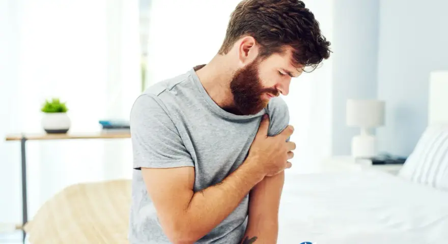 Uomo con barba che si tiene il braccio sinistro, avvertendo un fastidioso formicolio.