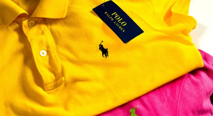 Żółta koszulka polo z czarnym polo ralph lauren znaczek. Obok różowa koszulka z zielonym logo.