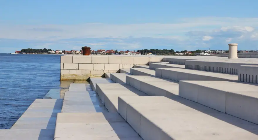 Kamienne schody nad morzem, z widokiem na miasto w oddali. Zadar co warto zobaczyć - idealne miejsce na spacer.