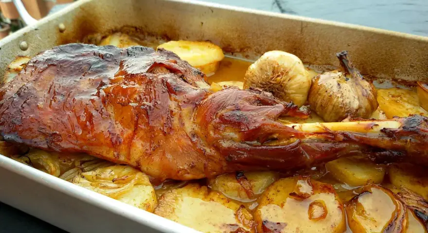 Paletilla de cordero asada al horno con patatas y ajos.