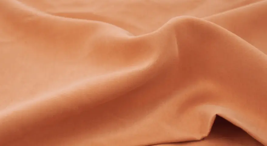 Miękka, pomarańczowa tkanina. Zastanawiasz się, **tencel co to**? To ekologiczny materiał o jedwabistym chwycie, idealny na letnie ubrania.