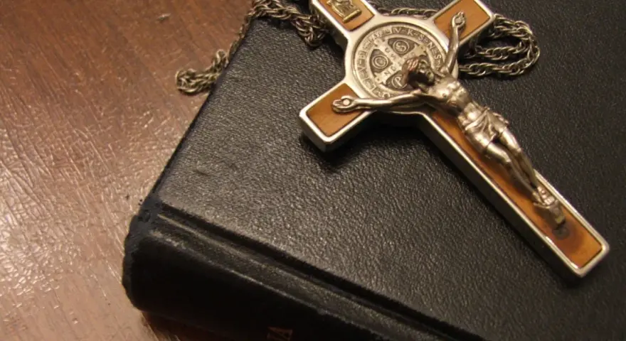 Krzyż z Jezusem i łańcuszek na czarnej księdze, symbol wiary i nadziei, narzędzia, które mógłby mieć przy sobie egzorcysta.