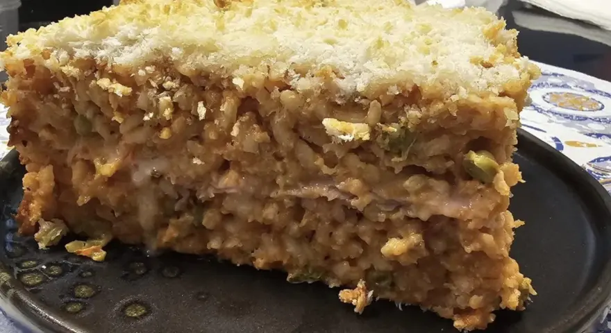 Una fetta di riso al forno, stratificato e dorato, con una crosta croccante di pangrattato.
