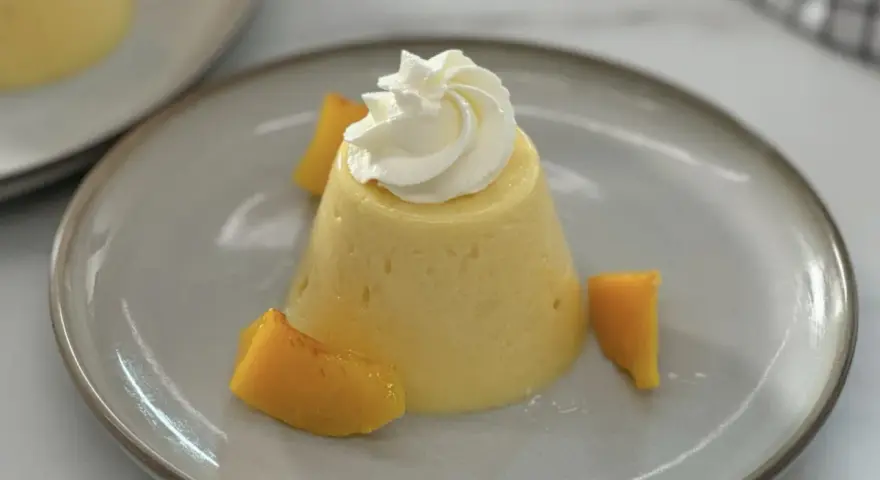 Postre de melocotón en almíbar con crema batida y trozos de melocotón.