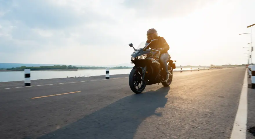 Motocyklista przemierza malownicze trasy motocyklowe pomorskie w blasku zachodzącego słońca.