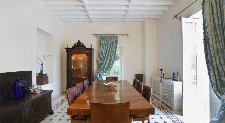 Elegancka jadalnia w stylu kolonialnym z drewnianym stołem, witryną i zdobioną skrzynią.