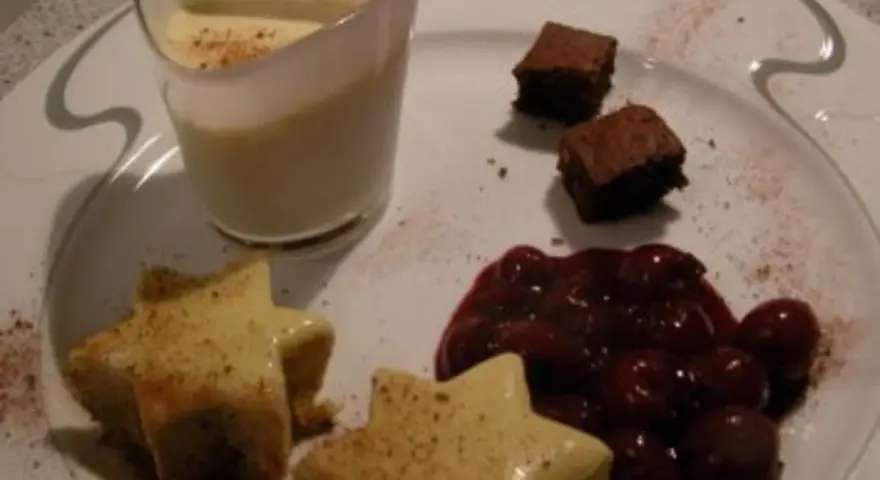 Sterne aus Zimtstern-Eis, garniert mit Kirschen und Brownies, serviert auf einem Teller.