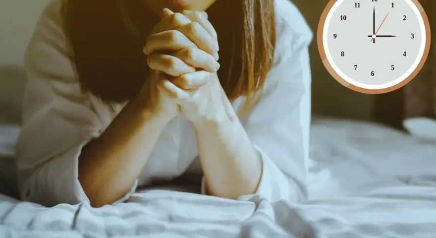 A woman is praying at 3am in the morning, her hands clasped tightly. The clock shows the early hour.