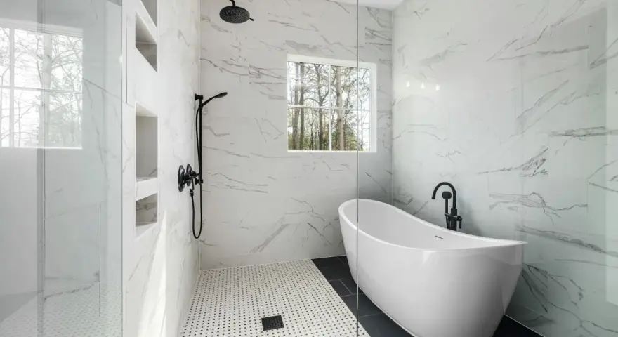 Salle de bain moderne avec baignoire îlot et douche vitrée, murs en porcelaine ou céramique effet marbre.