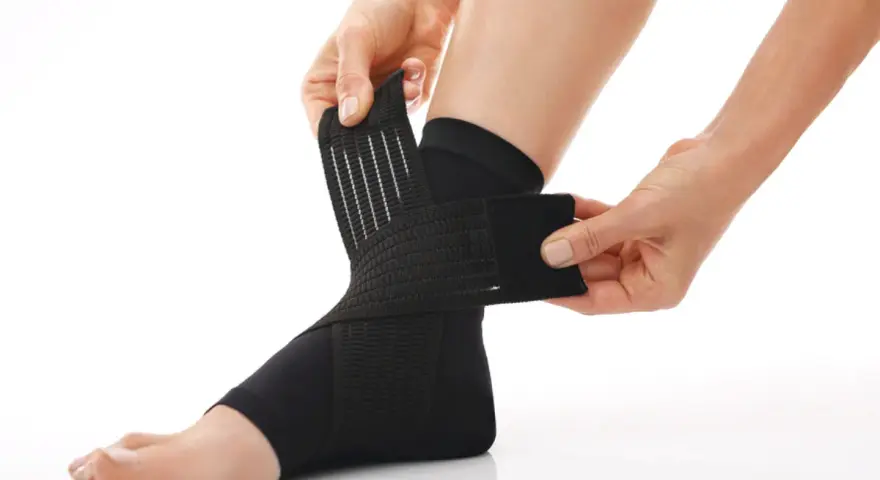 Hands adjust a black compression ankle brace, demonstrating how compression therapy works for support and recovery.