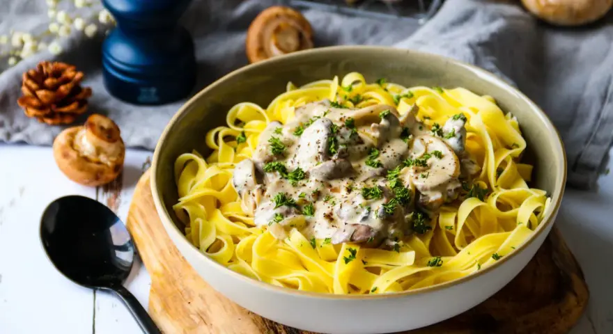 Un plat de pâtes tagliatelles garni d'une onctueuse sauce pour pâtes farcies aux champignons, parsemé de persil frais.