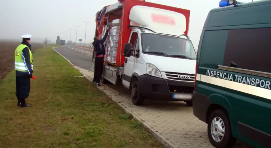 Kontrola drogowa: funkcjonariusz w kamizelce odblaskowej kieruje ruchem, obok biała ciężarówka z ładunkiem. Czy kierowca ma prawo jazdy kat b do 7,5 tony?