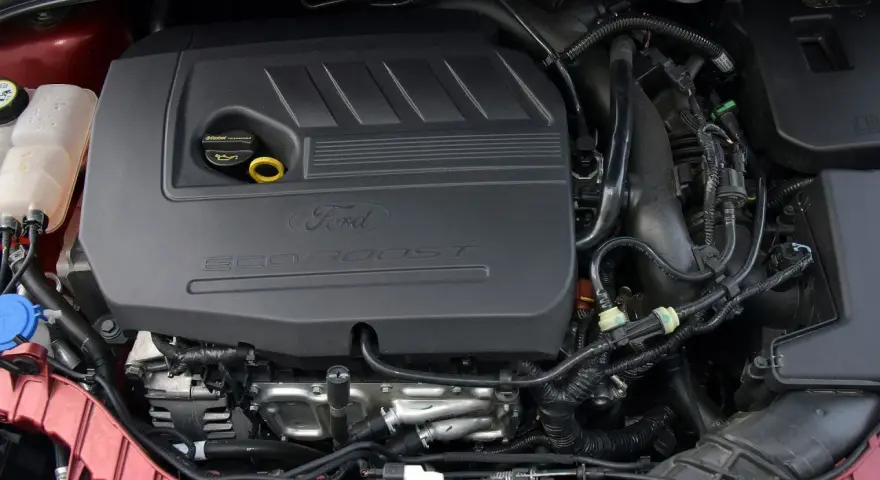 Silniki Ford Focus MK3 EcoBoost. Widok komory silnika z widocznym czarnym plastikowym elementem z napisem "Ford EcoBoost".