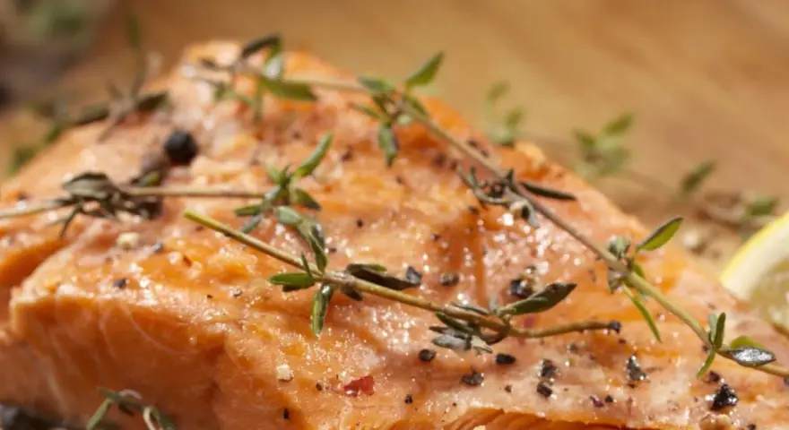 Delicioso salmón al horno, jugoso y dorado, con hierbas frescas y pimienta.