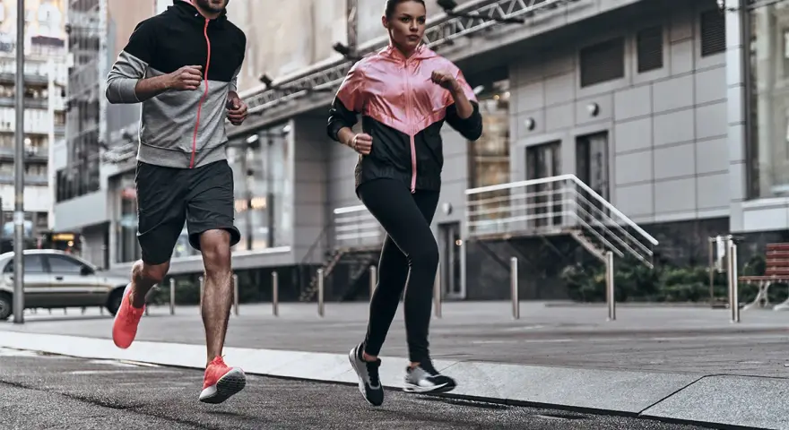 Coppia in corsa running in città, con abbigliamento sportivo colorato.