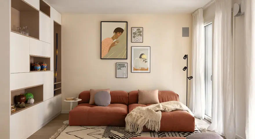Un soggiorno moderno con divano color terracotta e tappeto geometrico. L'arredamento è pensato per abbinare tappeto e divano, creando un ambiente accogliente.