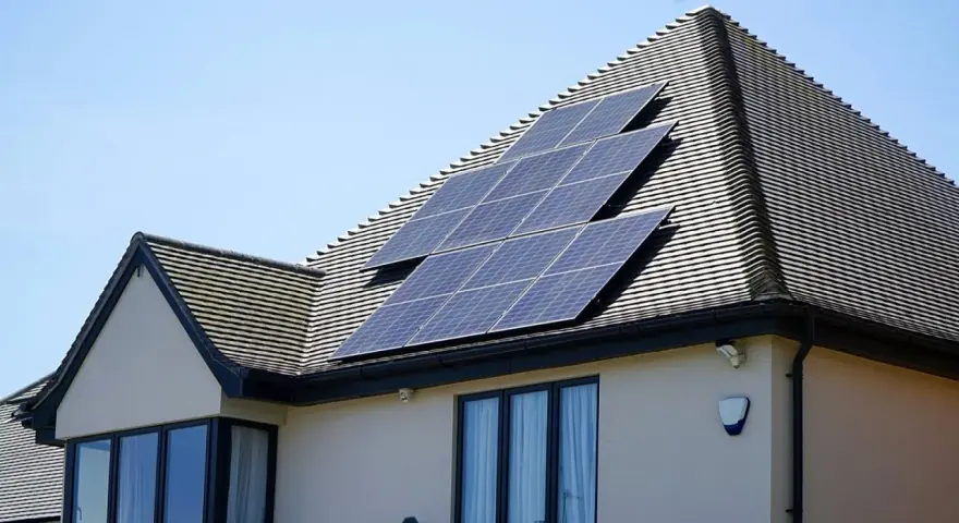 Panele fotowoltaiczne na dachu domu, działające jako agregator energii, łapią promienie słoneczne.