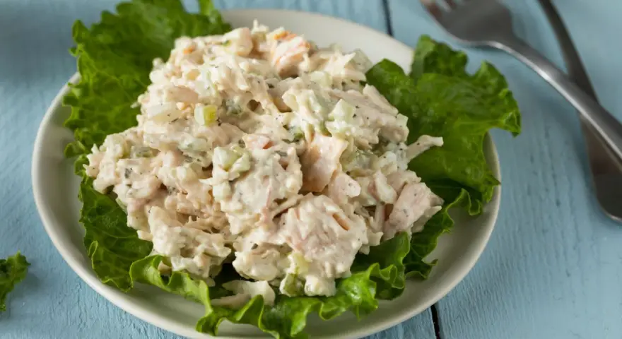 Un piatto di insalata di pollo della nonna, cremosa e ricca, servita su foglie di lattuga croccante.