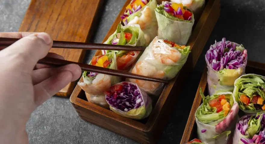 Chwytam pałeczkami świeże sajgonki z krewetkami, czerwoną kapustą i warzywami. Idealne co do sushi!
